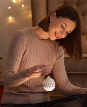 uma mulher sorrindo com uma bola de decoração de arvore natalina