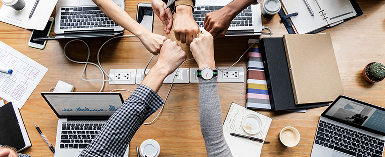 A imagem do artigo Agência especializada em Linx Commerce mostra mãos e computadores unidos para representar a parceria entre colaboradores