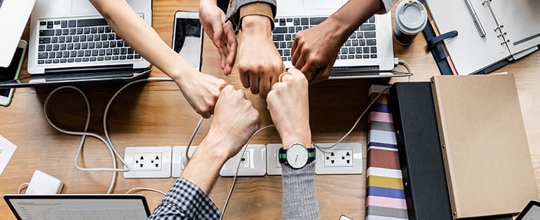 Com uma foto de punhos e computadores em avidência, a imagem é utilizada no artigo Agência de Marketing Digital: entenda a Cultura da FG